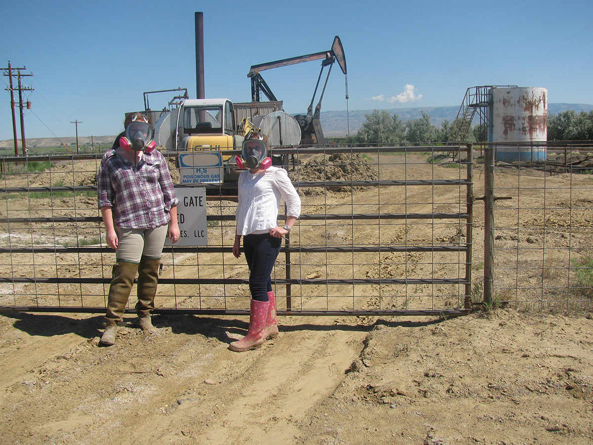 two women wearing gas masks in front of a natural gas operation